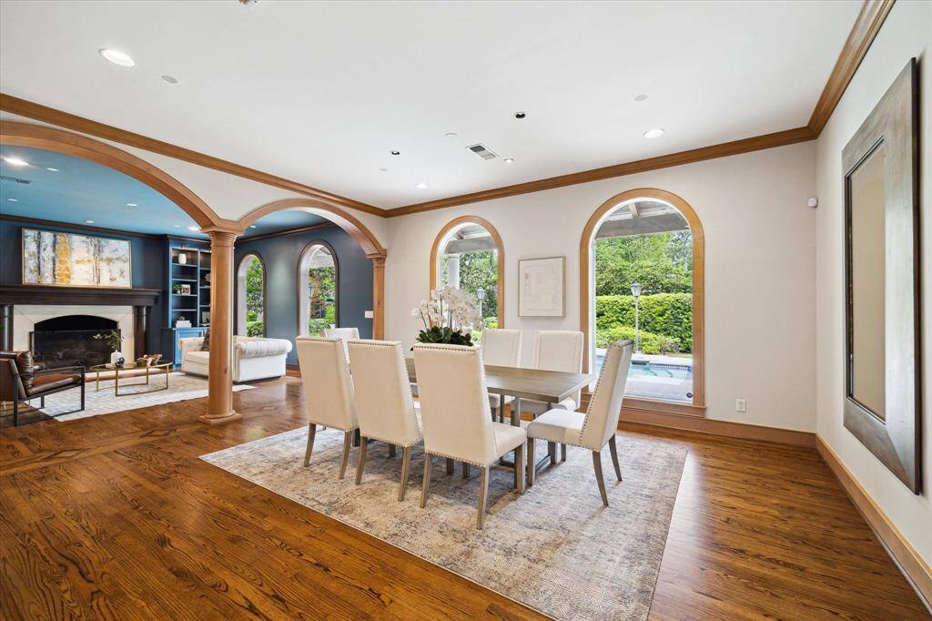 Elegant formal dining room wrapped in arched windows, offering tranquil views of the pool and grounds — perfect for intimate dinners or grand gatherings.