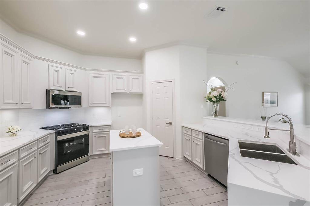 Vews towards the dining and family room over the quartz waterfall counters and breakfast bar. New under mount stainless steel sink with new stainless steel pull down faucet