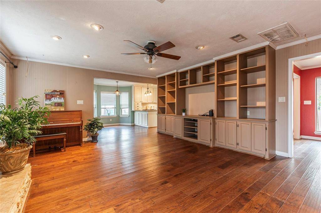 This large living area is warm and inviting, featuring custom-built shelving for stylish storage and display, along with a beautiful fireplace for cozy gatherings.