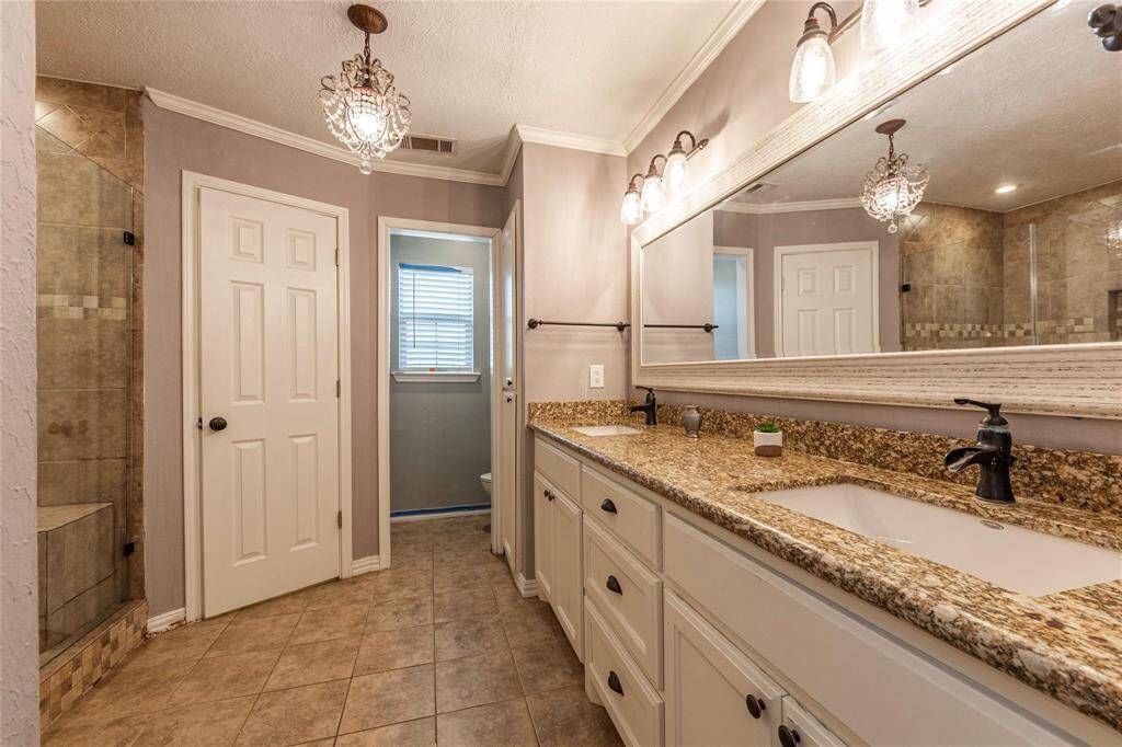 The primary bath has been fully updated with a walk-in shower, a double vanity, and modern finishes, creating a spa-like atmosphere right at home.