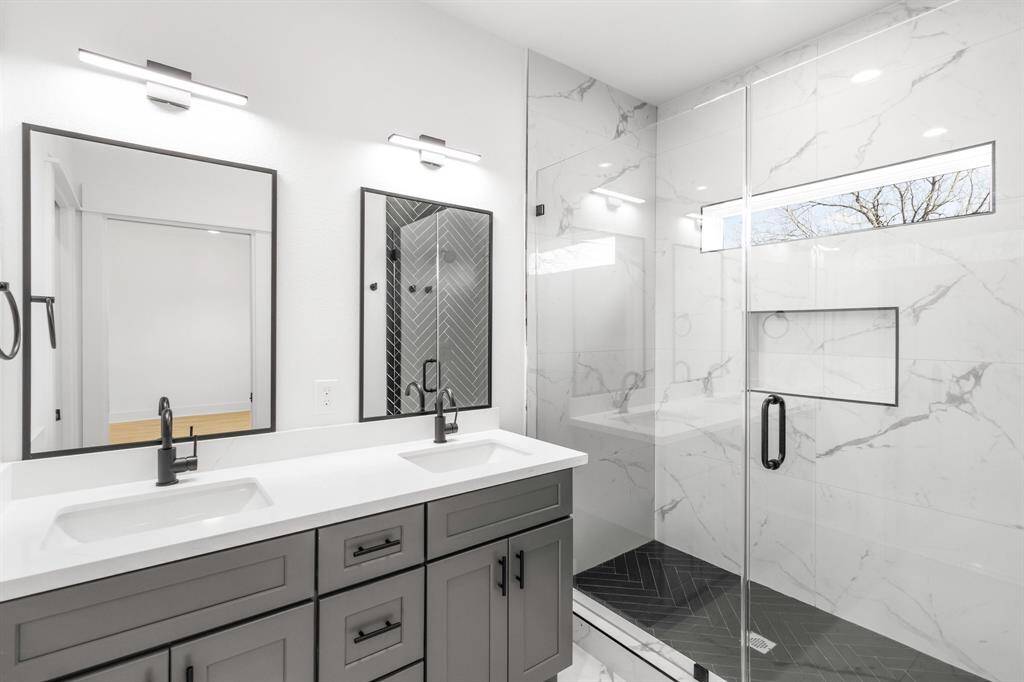 The primary bathroom features modern finishes, double sinks and walk-in shower.