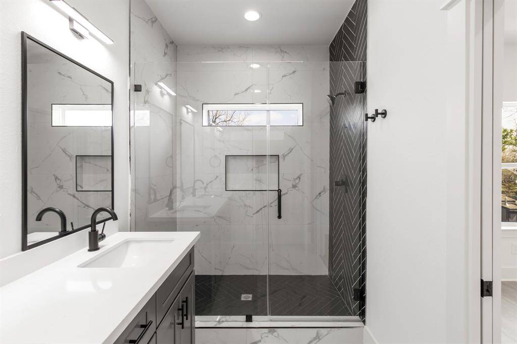 The primary bathroom offers a large shower with modern details.