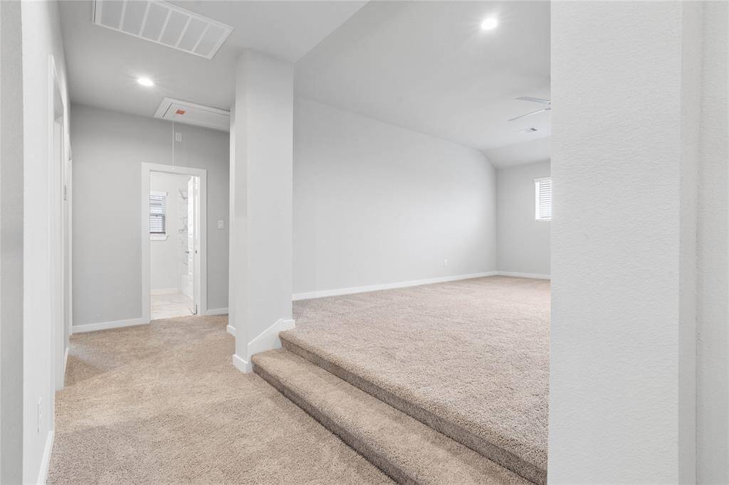 The second floor game room is elevated and is very spacious. Here is a view of the second floor looking at the game room, a secondary bathroom, and hallway leading to secondary bedrooms.