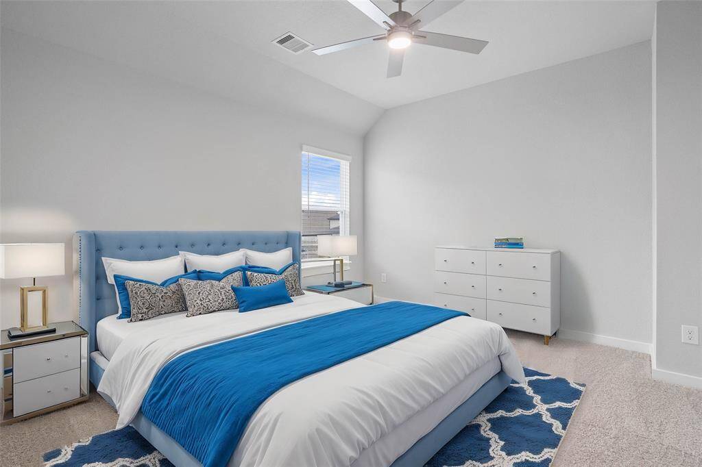 Secondary bedroom features plush carpet, custom paint, ceiling fan with lighting and a large window with privacy blinds.