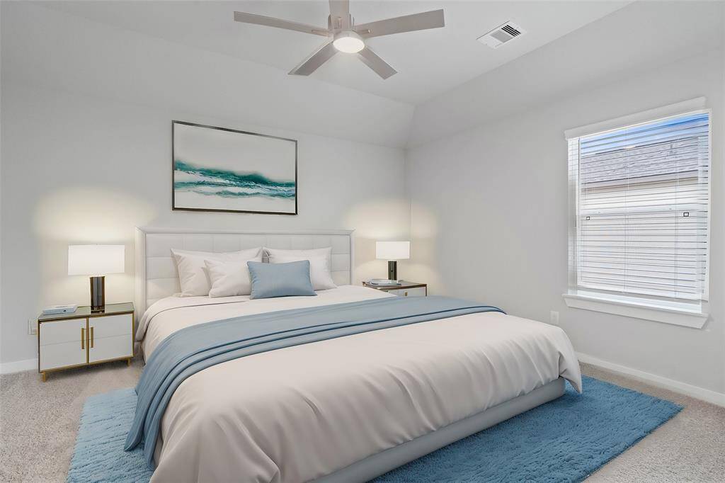 Secondary bedroom features plush carpet, custom paint, ceiling fan with lighting and a large window with privacy blinds.