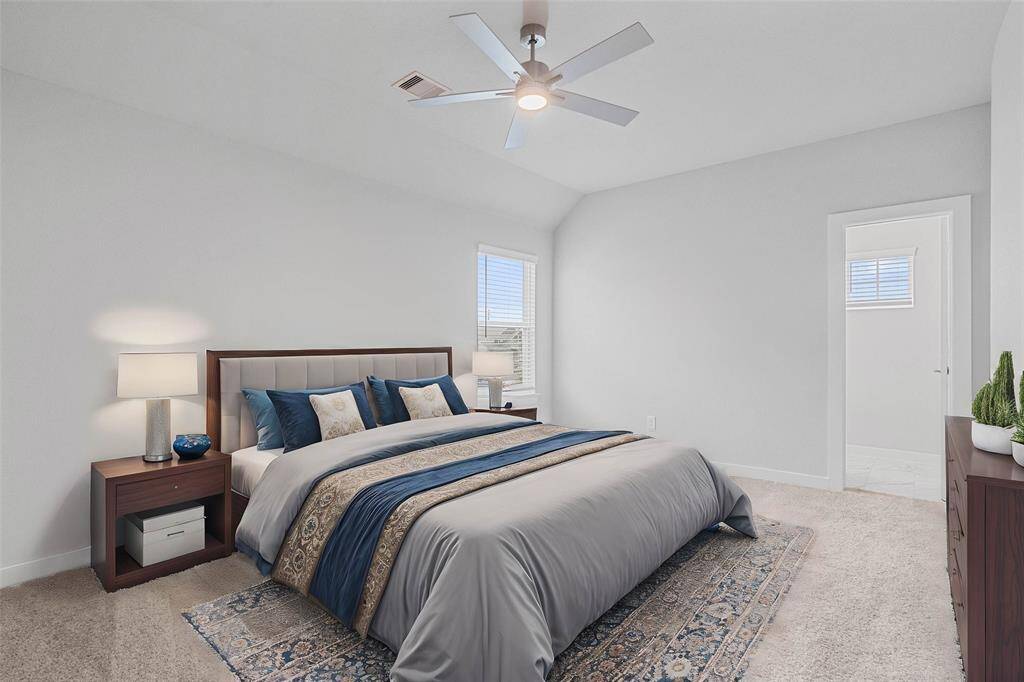 Secondary bedroom features plush carpet, custom paint, ceiling fan with lighting and a large window with privacy blinds.