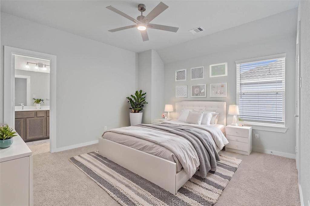 Secondary bedroom features plush carpet, custom paint, ceiling fan with lighting, large window with privacy blinds, and its own private access to a secondary bathroom.