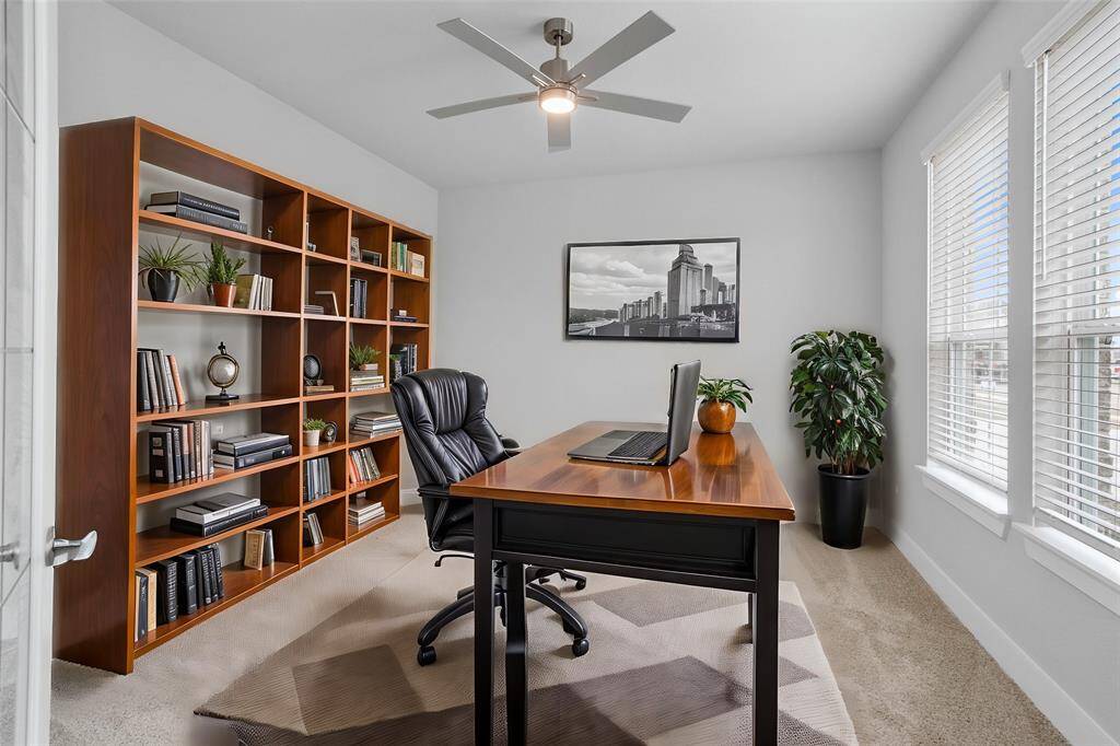Quietly nestled in front of the home is the handsome home office! Featuring plush carpet flooring, high ceilings with ceiling fan, large windows with privacy blinds, and custom paint!