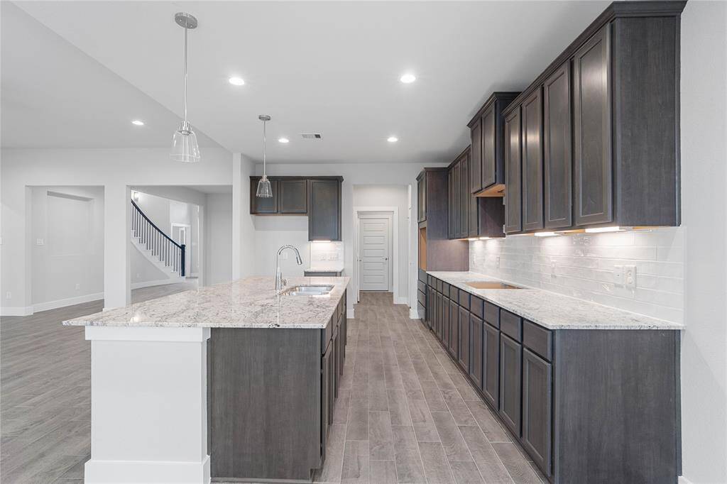 This kitchen is by far any chef’s dream! This spacious kitchen features high ceilings, stained wood cabinets, granite countertops, SS appliances, modern tile backsplash, recessed and pendant lighting, extended counter space, granite kitchen island with space for breakfast bar, and a walk-in pantry all overlooking your huge family room.