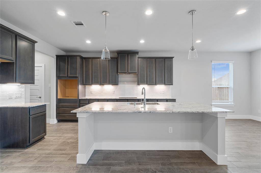 This kitchen is by far any chef’s dream! This spacious kitchen features high ceilings, stained wood cabinets, granite countertops, SS appliances, modern tile backsplash, recessed and pendant lighting, extended counter space, granite kitchen island with space for breakfast bar, and a walk-in pantry all overlooking your huge family room.