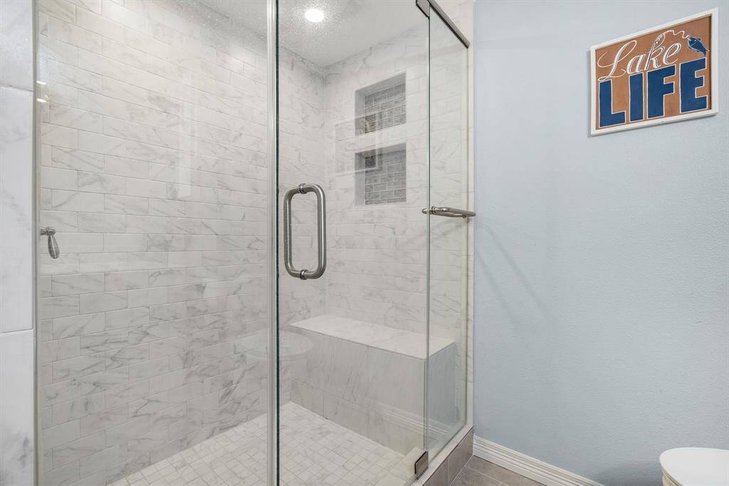 Oversized shower with bench and glass enclosure.