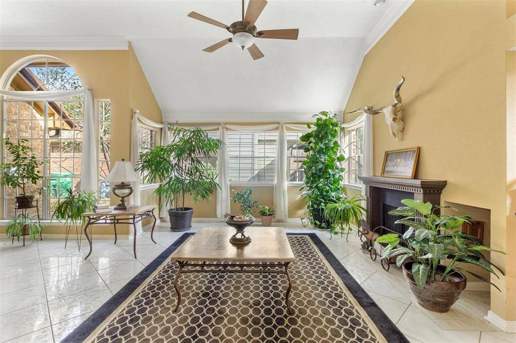 Family room features tile flooring, aceiling fan, high ceilings, and a wallof windows.