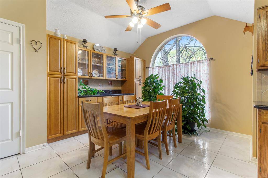 The breakfast room features tile floors, custom paint, ceiling fan, and large arched window.