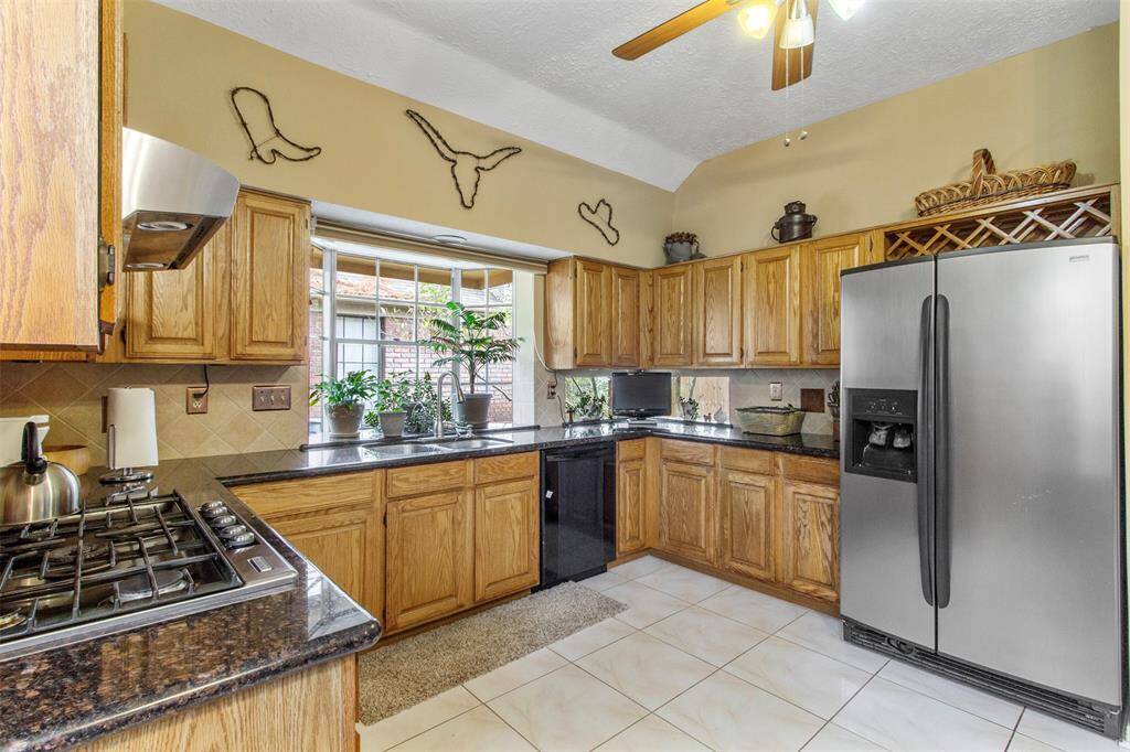 The kitchen features tile floors, wood cabinets, ceiling fan, high ceilings, and large windows over the sink.