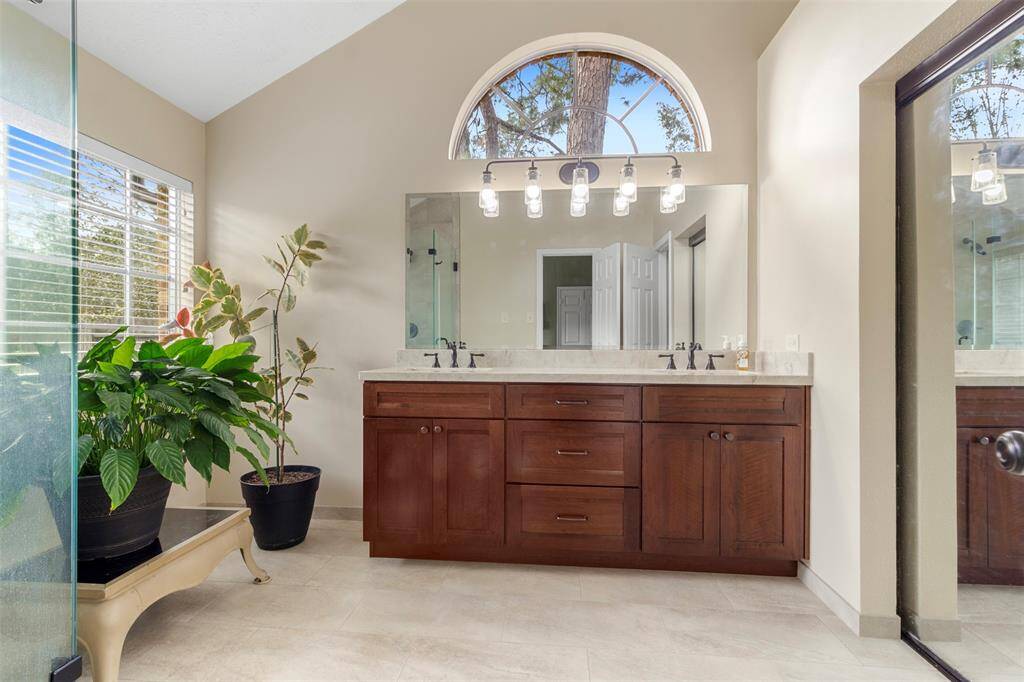 The primary bathroom features dual sinks, wood cabinets, tile floors, and large windows.