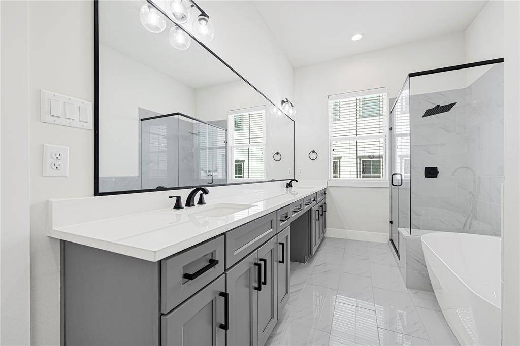 Spa-like en-suite bath featuring dual vanities, soaking tub, and glass-enclosed shower.