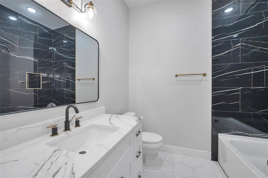 Secondary primary bathroom includes modern fixtures, a tub/shower, and stylish vanity