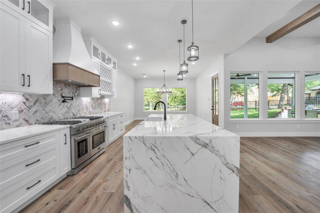 The chef’s kitchen is designed to impress with a six-burner gas range, pot filler, quartz countertops, oversized island, soft-closing drawers and cabinets, and walk-in pantry