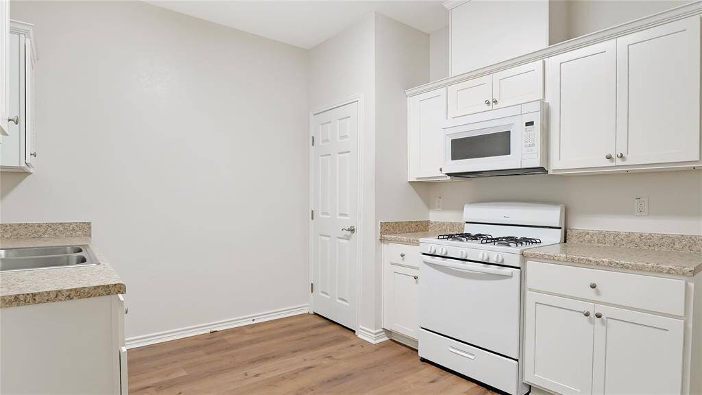 The kitchen is located towards the back of the home. It has a gas stove, a microwave, and lots of storage in the cabinets and pantry.