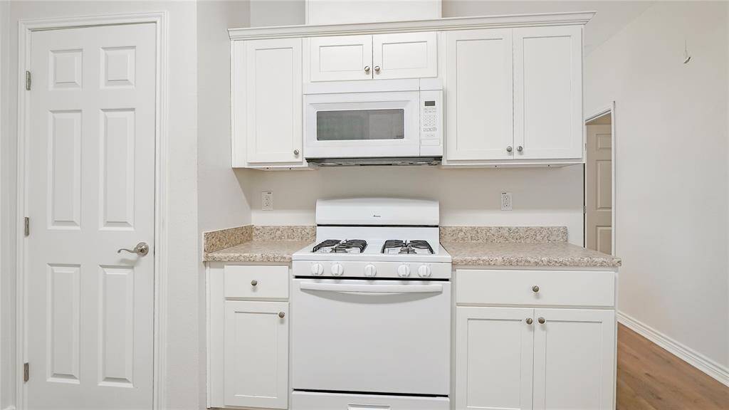 The kitchen is located towards the back of the home. It has a gas stove, a microwave, and lots of storage in the cabinets and pantry.
