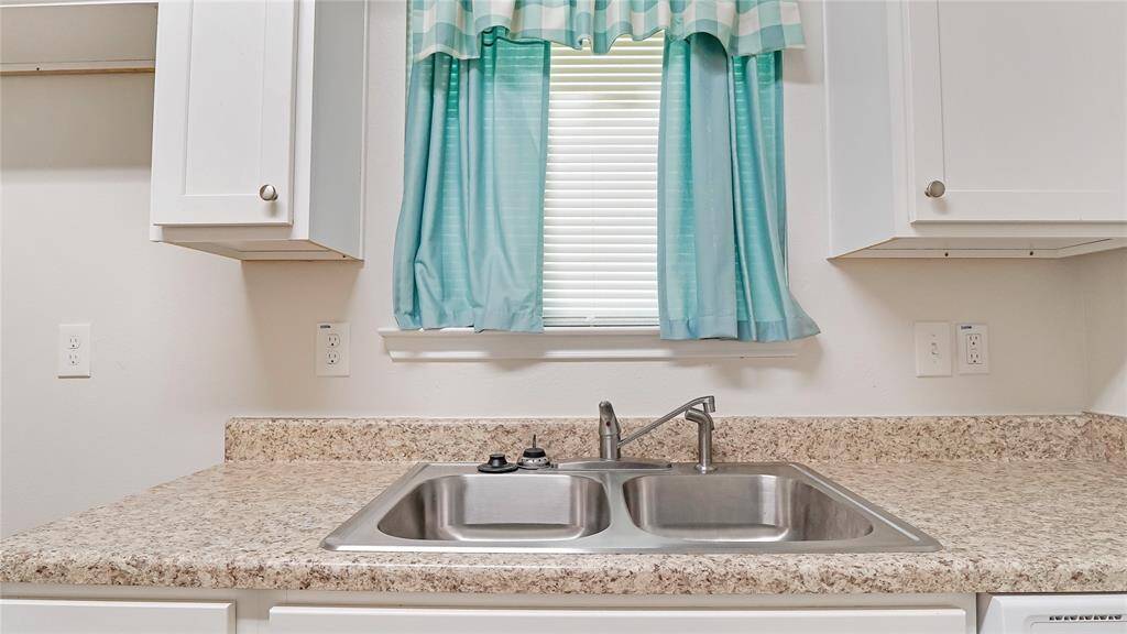 The kitchen is located towards the back of the home. It has a gas stove, a microwave, and lots of storage in the cabinets and pantry.