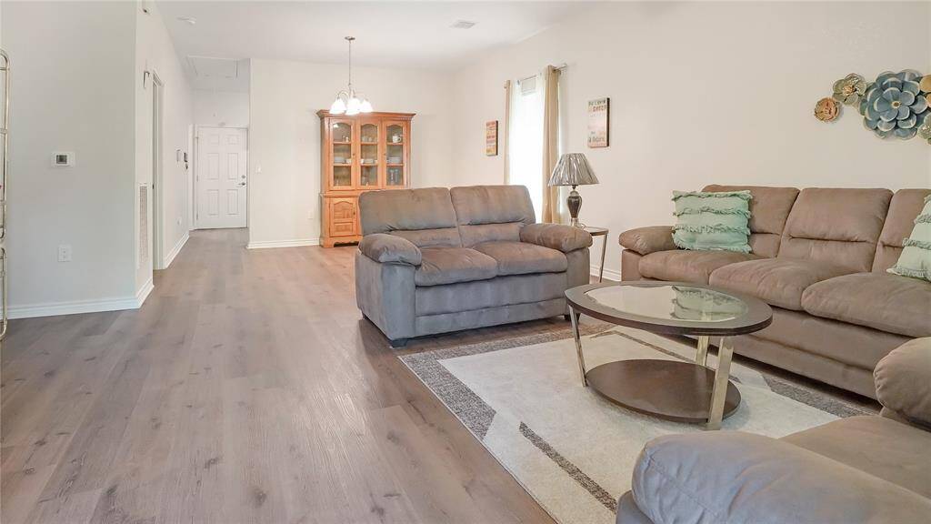 Bright and welcoming, this spacious living room features wood-look flooring, neutral tones, and an open layout perfect for relaxing or entertaining. Natural light and cozy seating make it feel like home.
