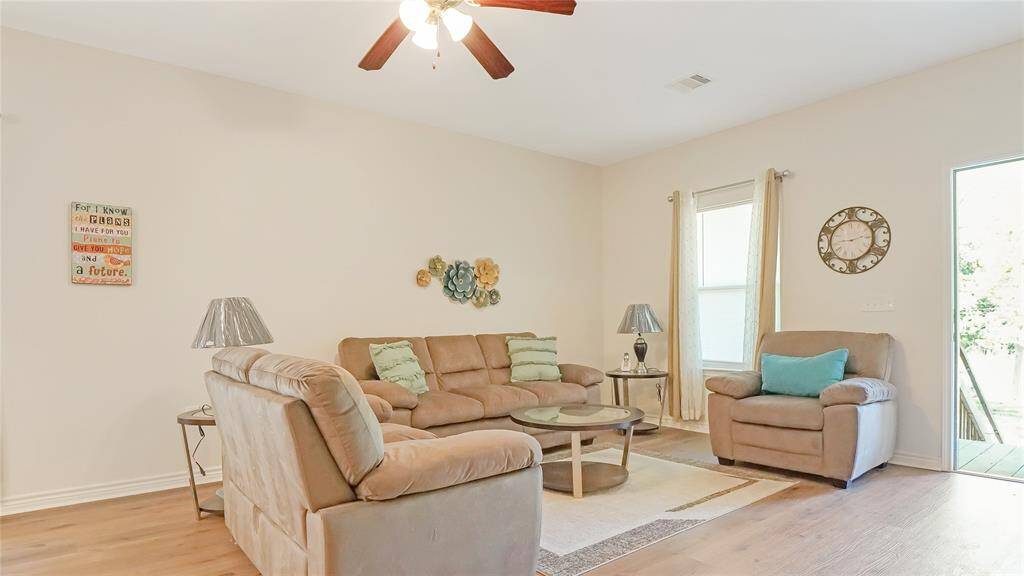 Bright and welcoming, this spacious living room features wood-look flooring, neutral tones, and an open layout perfect for relaxing or entertaining. Natural light and cozy seating make it feel like home.