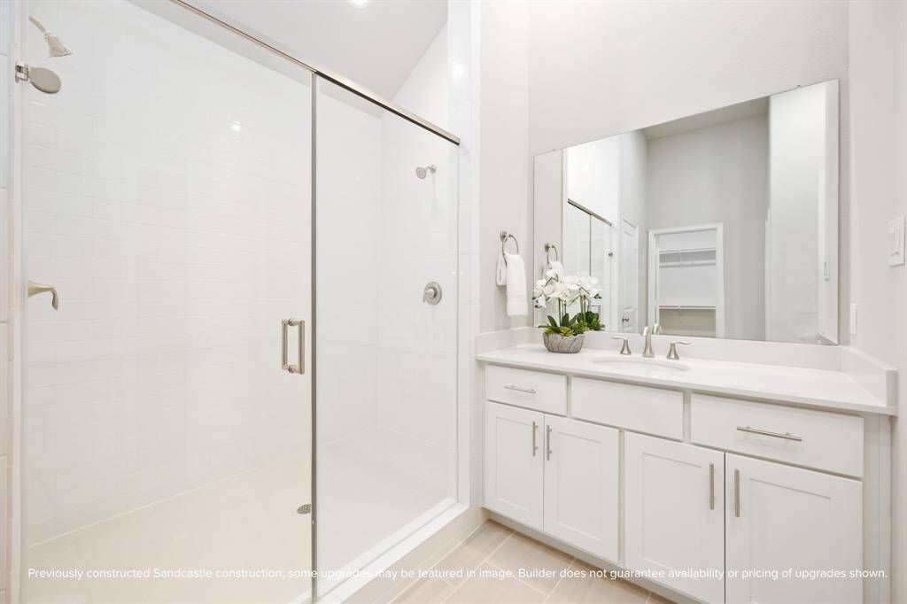 A wide quartz vanity with sleek undermount sinks offers plenty of prep space, framed by soft lighting and a full-width mirror.