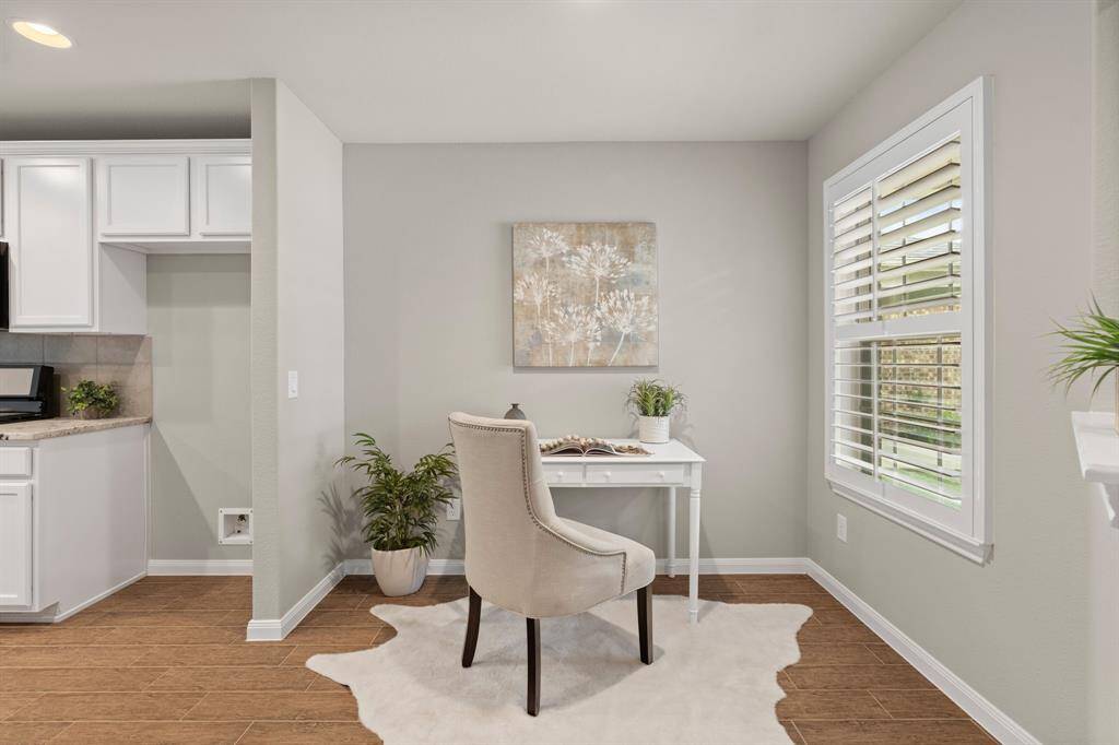 Enjoy a cup of coffee at your office/study area in the nook by the kitchen. Indulge in the elegant craftsmanship of custom plantation shutters, adding a touch of sophistication and character to this cozy space.