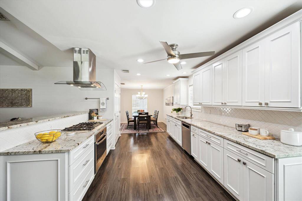 A long stretch of Brazilian granite countertops and Kraftmade cabinetry offers abundant prep space and storage, all in a light-filled, open-concept layout with recessed lighting overhead.