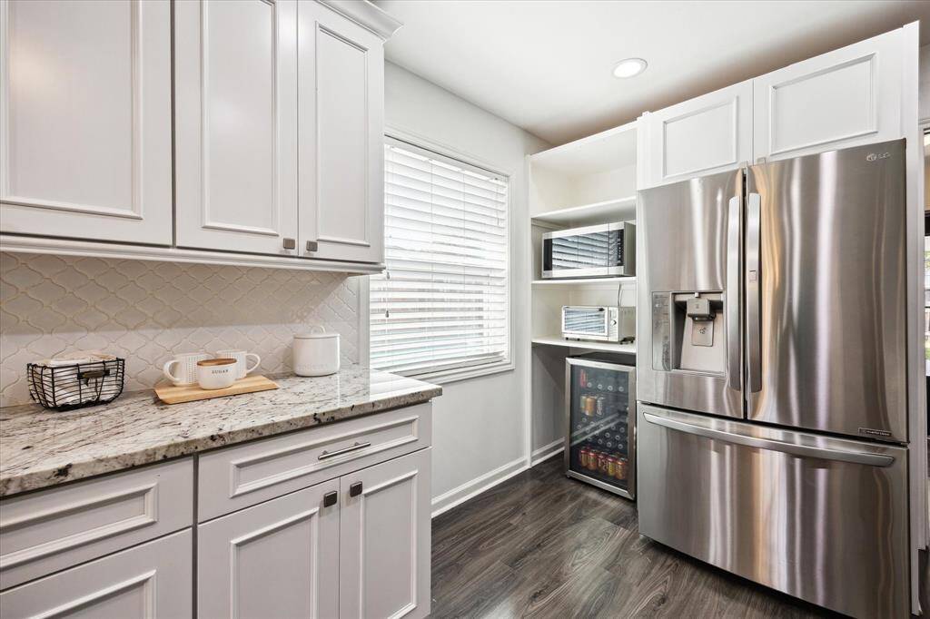 Stainless steel appliances, including a French-door refrigerator, are surrounded by additional storage and great natural light.
