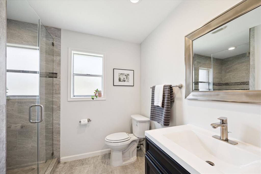 The airy, light-filled en-suite bath was renovated in 2019 and features a large stand-alone shower with a sleek frameless glass door, offering a modern and spa-like feel. While it currently has a single sink vanity, the space can easily accommodate double sinks if desired. This bath also features a good-size linen closet.