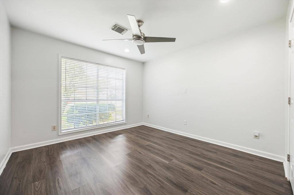 This spacious front bedroom enjoys abundant natural light thanks to its southern exposure, creating a bright and inviting atmosphere throughout the day. Recessed lighting adds a modern touch.