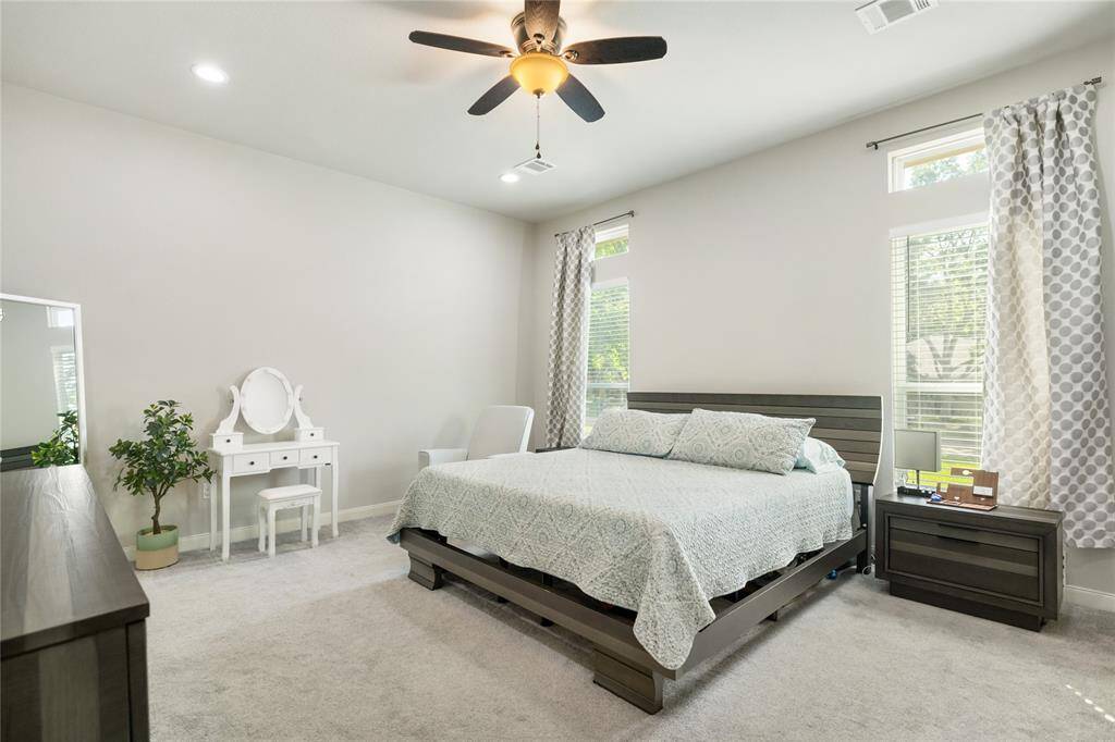 The primary suite offers a spacious retreat with soothing neutral tones, large windows that fill the room with natural light, and a ceiling fan for added comfort. It’s a serene space designed to help you unwind and recharge at the end of each day.