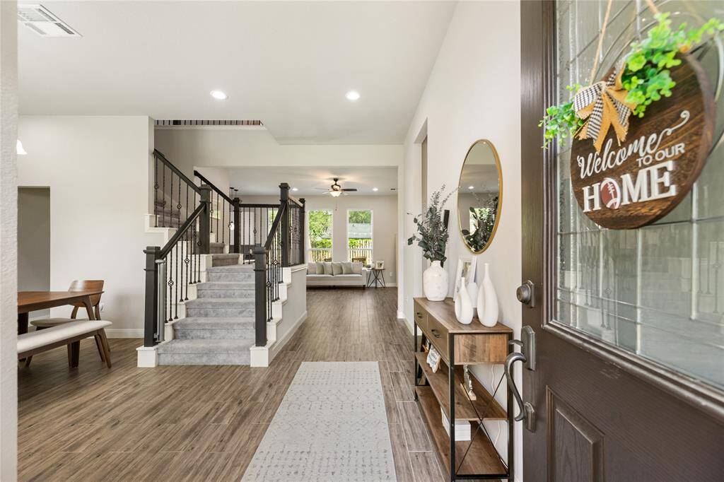 Step into a bright and welcoming entryway with rich wood flooring and natural light streaming in from nearby windows. The graceful staircase and open hallway guide you toward the heart of the home, offering a glimpse of the spacious layout ahead—an ideal setting for everyday moments and special gatherings alike.