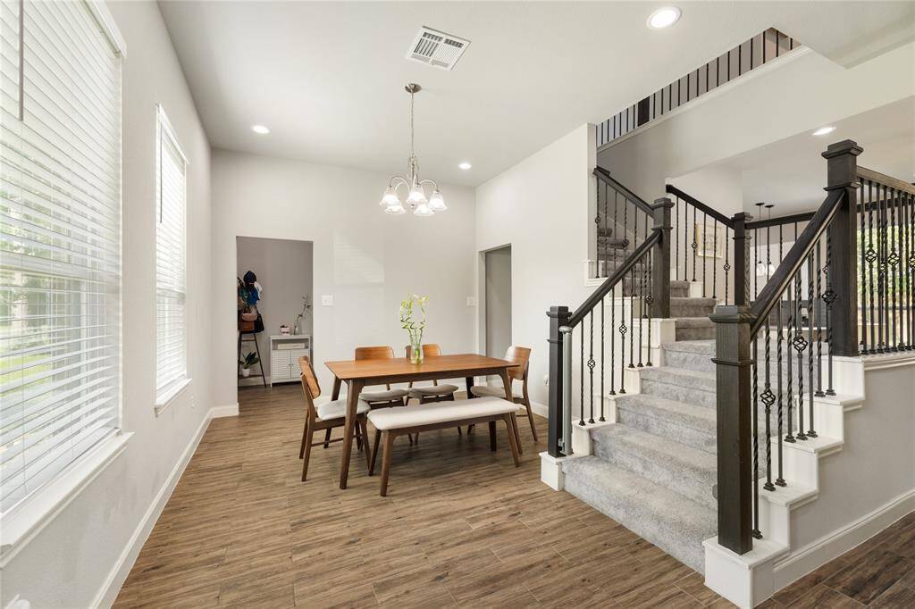 This light-filled dining area features warm wood flooring, contemporary lighting, and expansive windows that bring in natural sunshine. With an open flow leading to the staircase and surrounding spaces, it’s the perfect spot to enjoy meals, host gatherings, and create lasting memories.