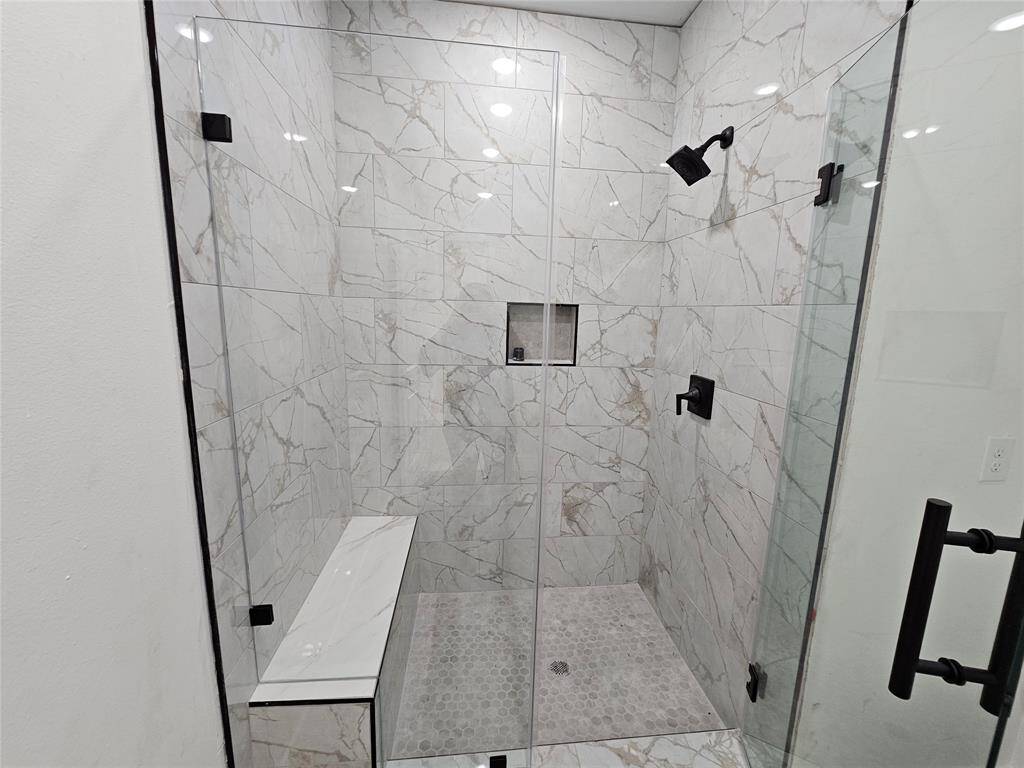 Spacious primary walk-in shower with bench, and upgraded tile.