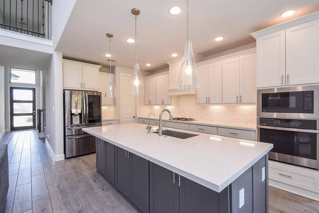 Modern Gourmet kitchen with extended ivory stone island bar, sleek stainless steel appliances and a gas cooking range.