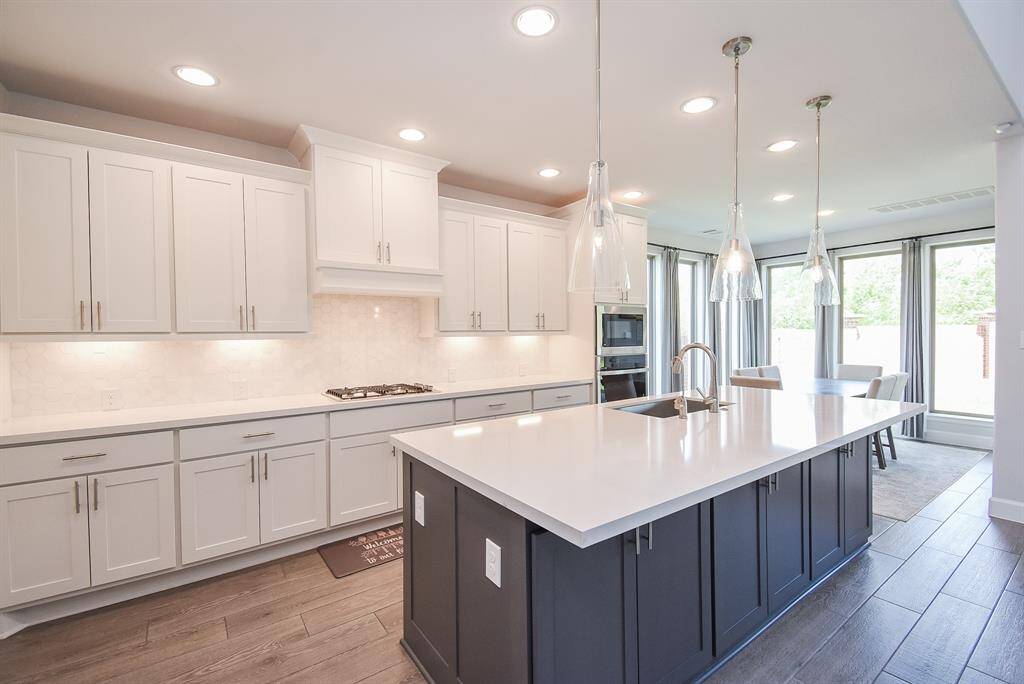 Kitchen has under cabinet lighting, lots of cabinet storage, kitchen island doubles as a breakfast bar, and glass pendant lighting