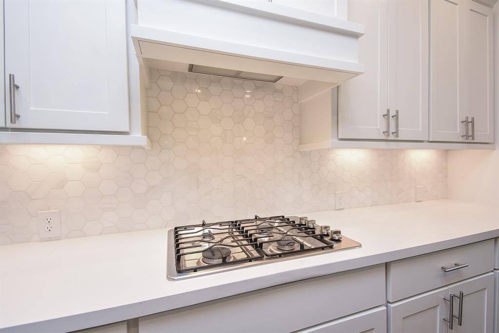 Who wouldn't love this bright and clean white on white backsplash, white stone counter tops, gas burning range. Lots of counter space and 42" flat-front cabinets.