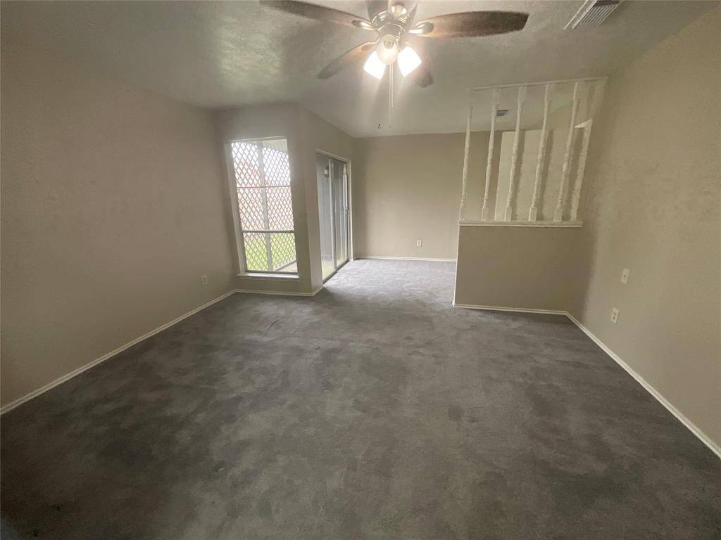 Spacious primary bedroom featuring cozy carpet, a ceiling fan, and abundant natural light with easy access to the outdoors through sliding doors.