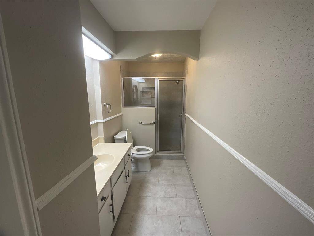 Modern and efficient second bathroom featuring a sleek walk-in shower, ample storage, and bright lighting. Perfect for guests or family use.