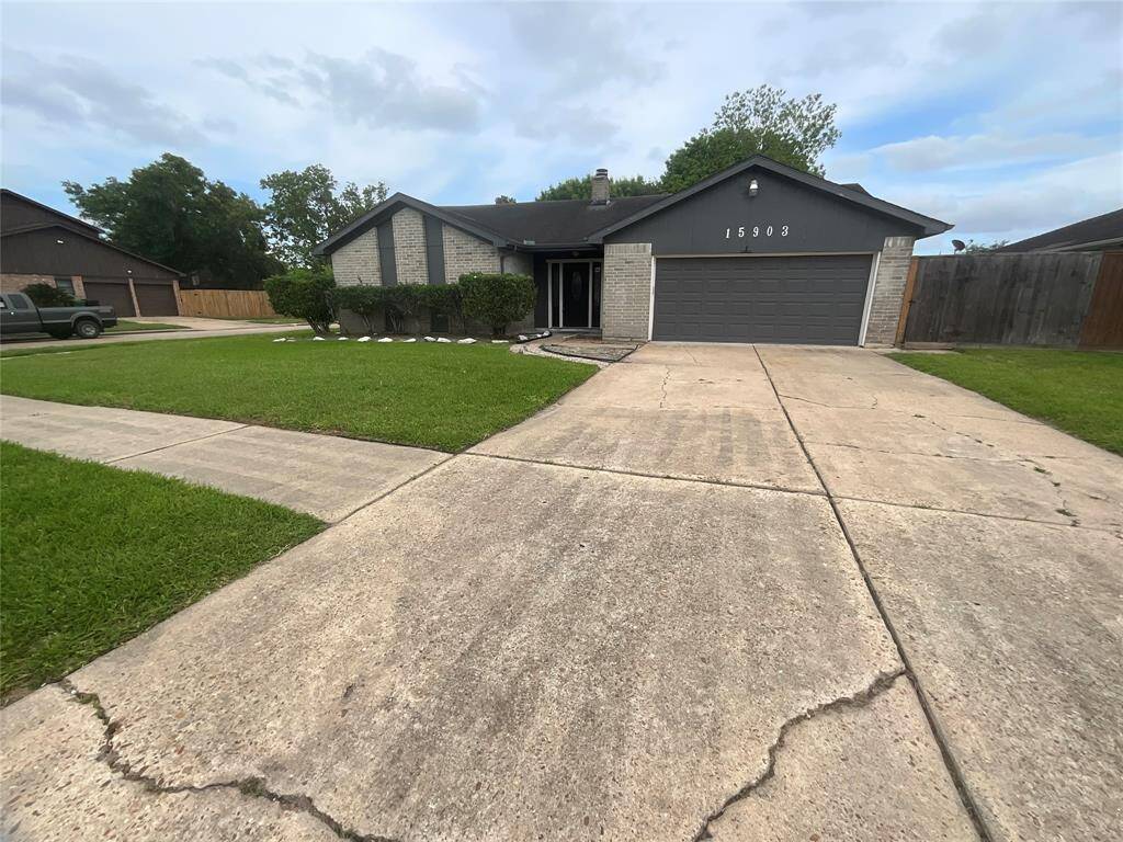 A single-story home with a modern gray exterior, featuring a two-car garage and a spacious driveway. The front yard is well-maintained with a neat lawn and shrubs, offering a welcoming curb appeal.