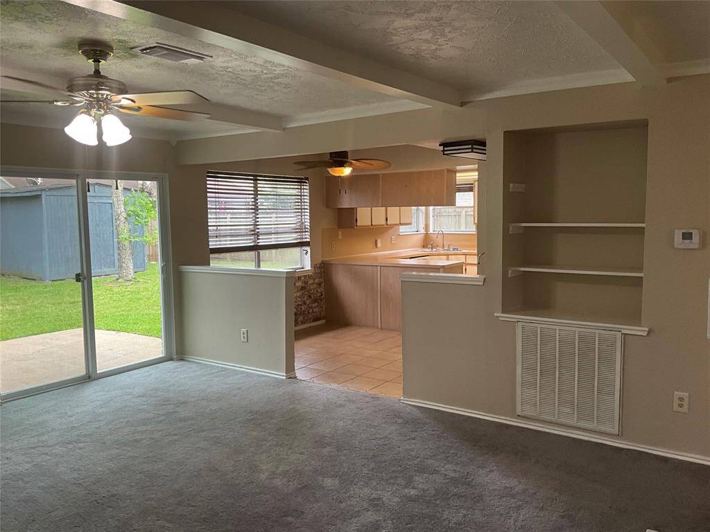 Bright and inviting living room with sliding glass doors leading to a lush backyard. Open layout seamlessly connects to the kitchen, perfect for entertaining.