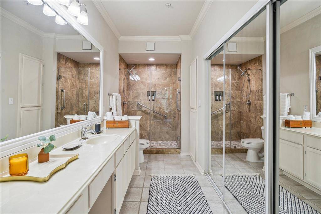 the primary bathroom includes a walk-in shower, long vanity and a wall of closet
