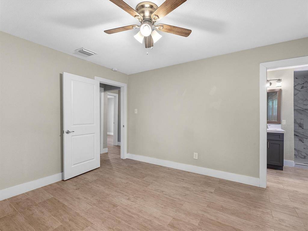 Wood flooring flows seamlessly between the hallway, primary bedroom and bathroom.