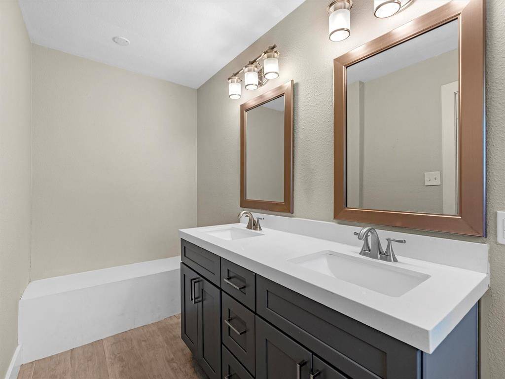 Updated vanity includes double sinks with modern mirrors and lighting fixtures.