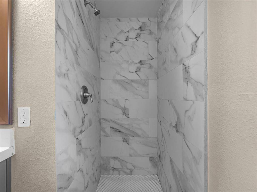 Beautiful designer floor-to-ceiling wall tiles in the primary shower enhance the luxurious feel.