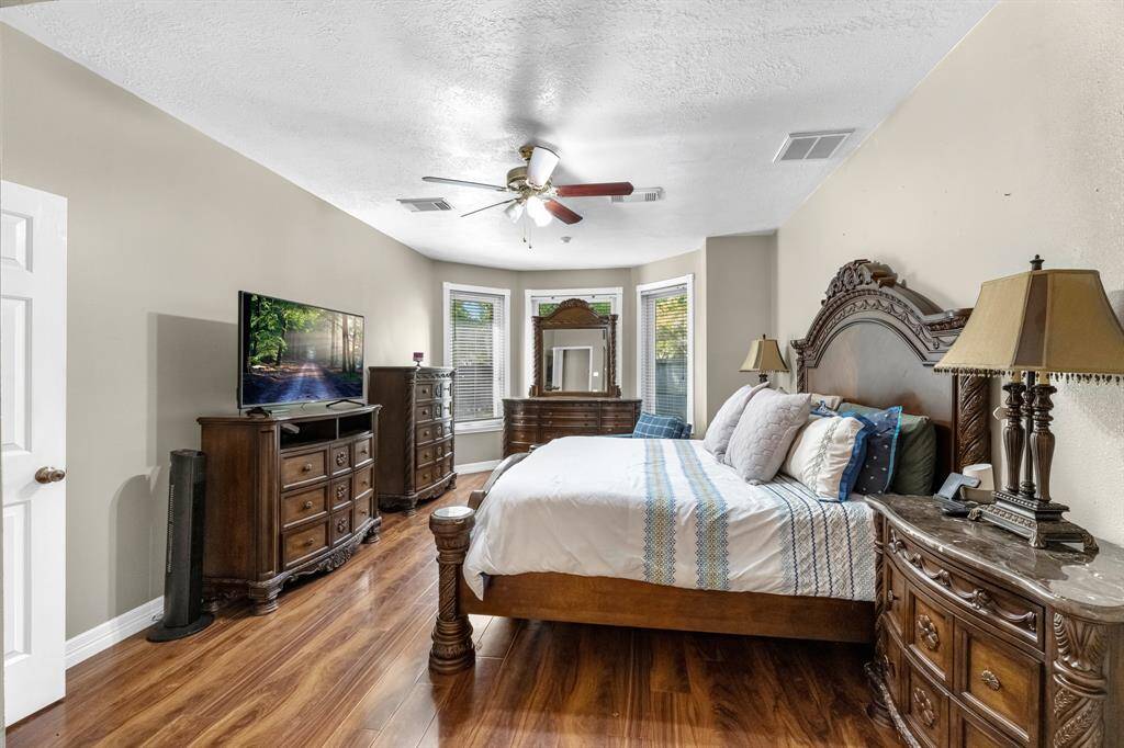 Experience luxury in this elegant bedroom featuring rich wood furnishings, a spacious layout, and abundant natural light. Perfect for relaxation and comfort.
