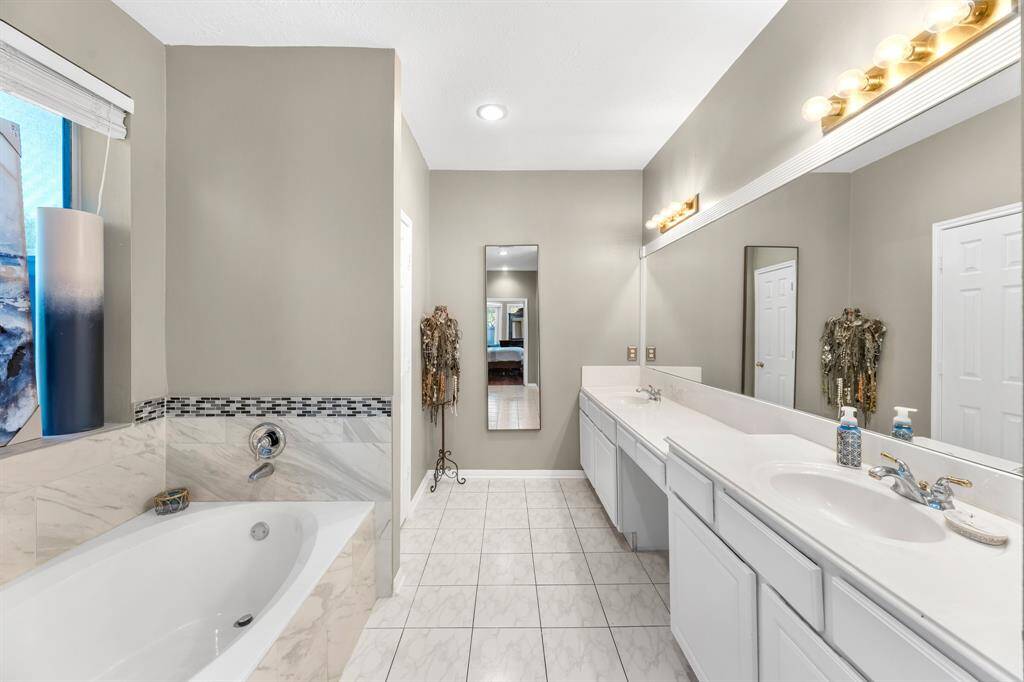 Experience luxury in this elegant bathroom with a spacious tub, sleek tiling, and ample counter space, perfect for unwinding.